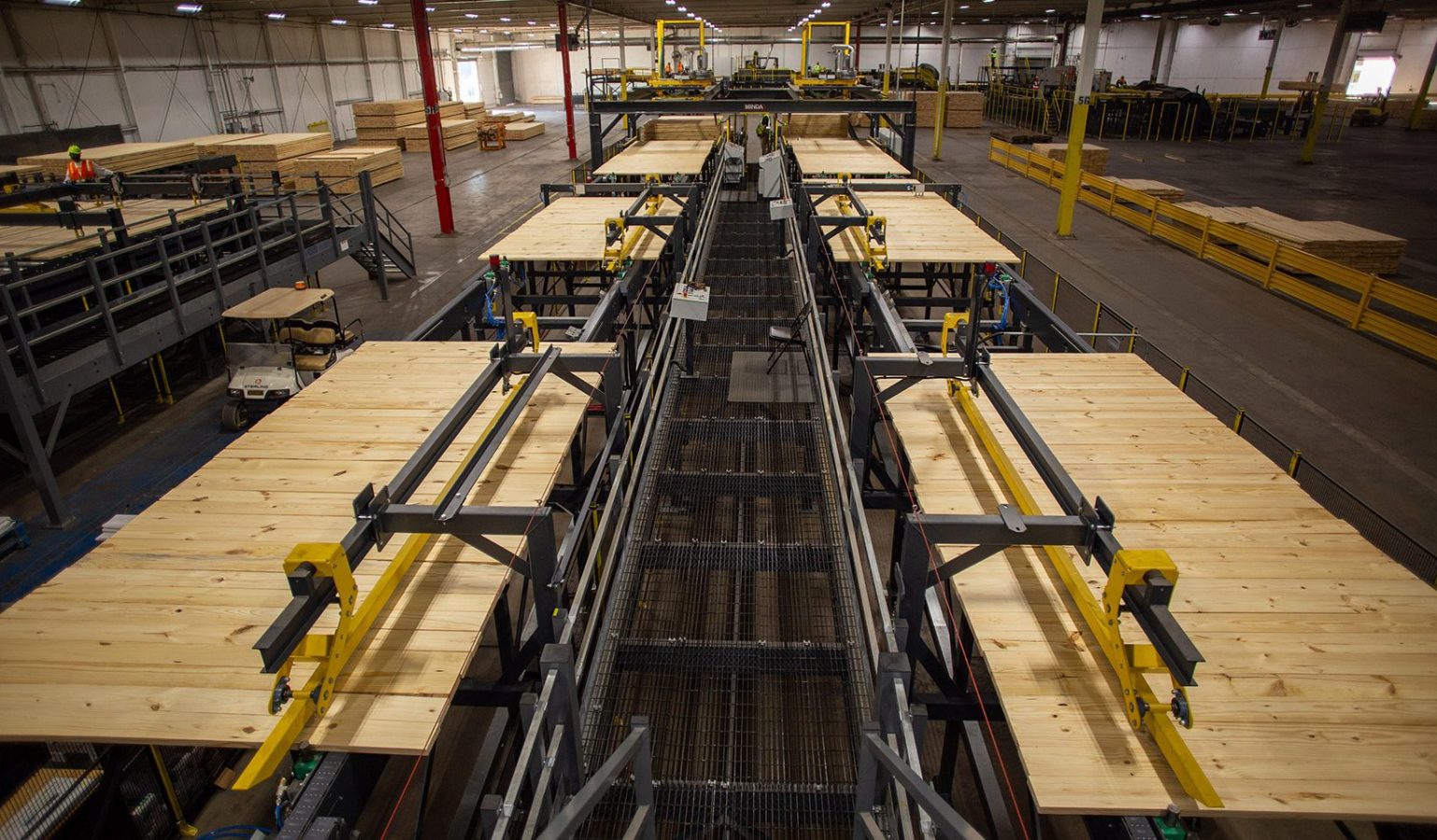 The image shows Sterling Structural's factory with wooden planks on conveyor systems and overhead machinery, viewed from above.