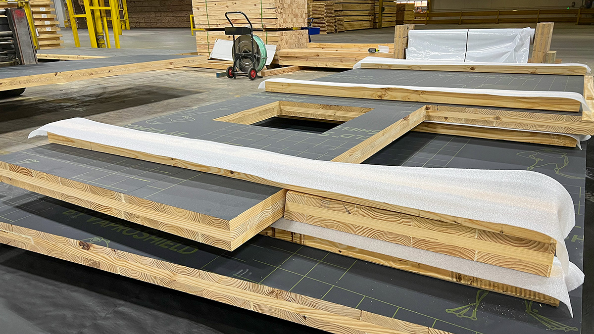 Stacks of cross-laminated timber (CLT) panels wrapped in protective material, inside Sterling Structural's warehouse.