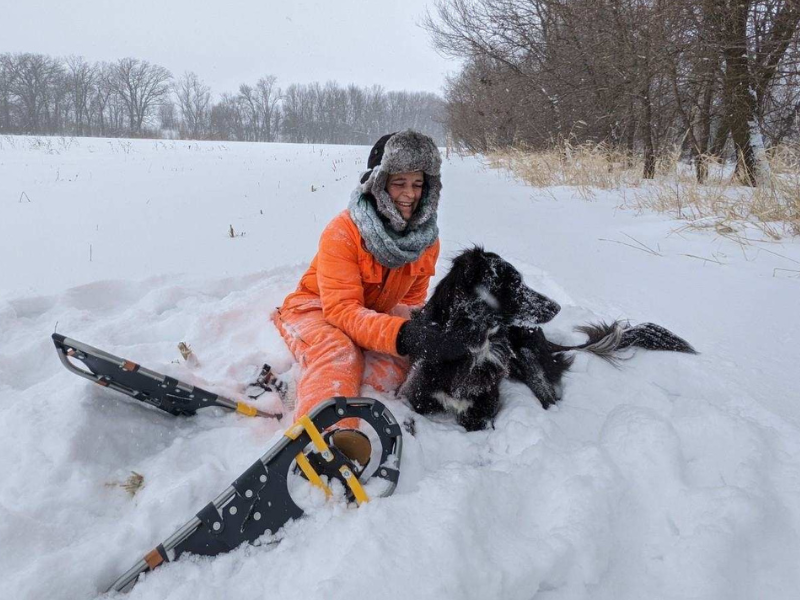 Michaela Harms with a black dog snowshoeing