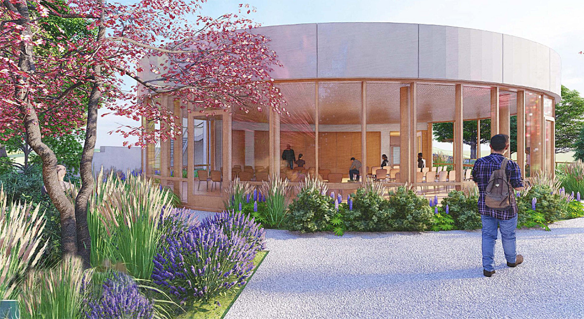 The image shows a circular glass-walled building surrounded by plants and flowers, with a person walking toward it and people sitting inside.