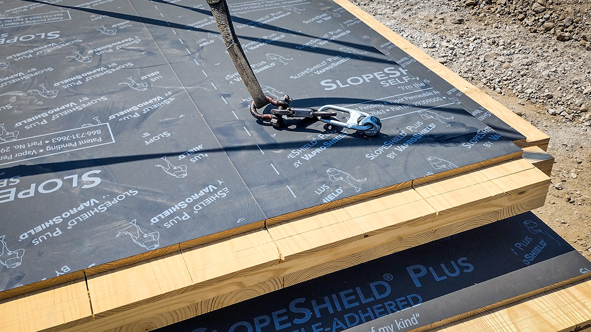 Close-up of a CLT panel covered with Vaproshield SlopeShield Plus membrane during installation, with a securing strap visible.