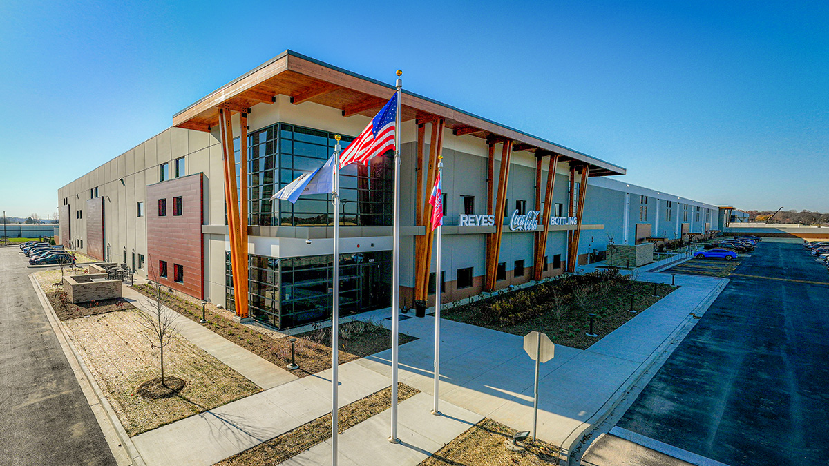 A building facade with signage reading "Reyes Coca-Cola Bottling," featuring wooden beams and windows.