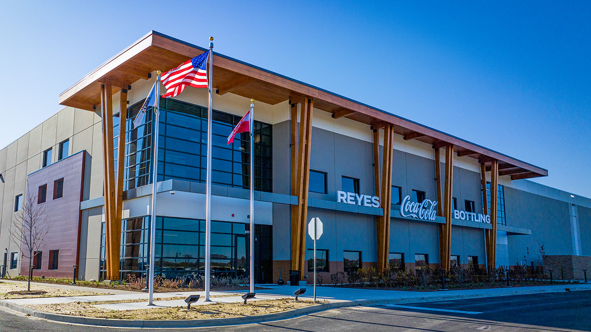 A building facade with signage reading "Reyes Coca-Cola Bottling," featuring wooden beams and windows.